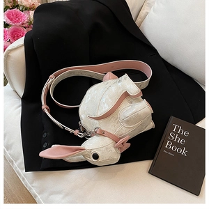 Detail of cute rabbit shoulder bag with pink bow on a black suit and roses