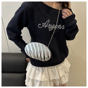Macro view of silver shell-shaped evening bag with metallic wave pattern and chain strap