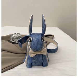 Detail of blue bunny crossbody bag with gold splatter pattern and white bowknot
