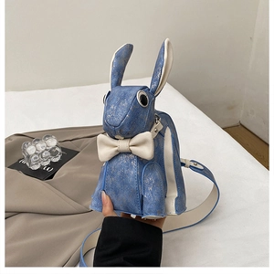Close-up of blue bunny shoulder bag with golden spots and a white ribbon detail