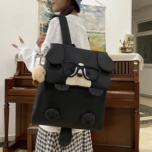Cute black cartoon dog backpack for girls with ears and plush charm on a model