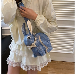 Detail view of the light blue rabbit shoulder bag with a cute bow on beige dress