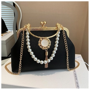 Detail of black vintage shell bag with pearl decor, gold fringes, and metal chain