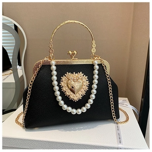 Close-up of black litchi leather shell bag with golden heart hardware and pearls