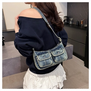 Detail of vintage washed denim underarm bag with metal buckles on cargo front pockets