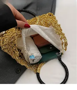 Detail der gold gewebten Strandtasche mit runden Griffen und geräumiger Innentasche