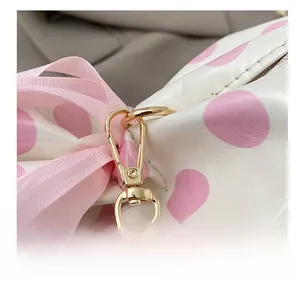 Detail of pink polka dot bag with satin bow and golden metal hook attachment