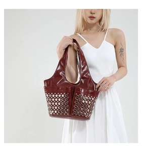 Detail of dark red punk tote bag with silver round rivets on glossy synthetic leather