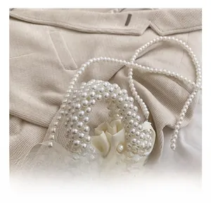 Détail d'un mini sac en perles fait main avec rose en satin et bandoulière perlée