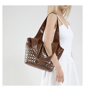 Close-up of shiny dark brown patent leather shoulder bag with silver punk metal rivets