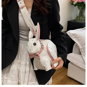 Detail of cute white bunny crossbody bag with pink bow and long shoulder strap on a model