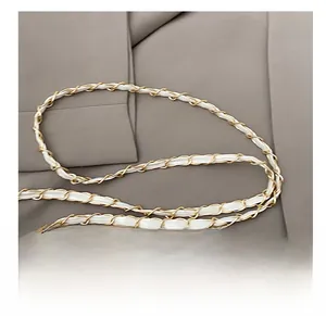 Close-up of golden metal chain woven with white leather strap for shoulder bags