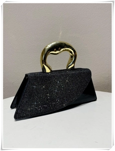 Detail of triangular evening bag with black glitter finish and gold irregular handle