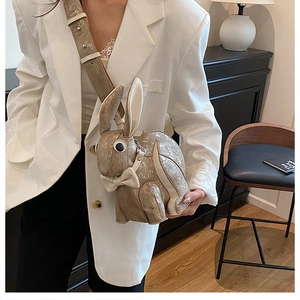 Detail of champagne gold bunny crossbody bag with bow accent and cracked leather texture