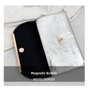 Vue détaillée d'une pochette argentée avec fermoir magnétique doré et doublure noire