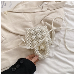 Close-up of handmade white pearl woven bag with drawstring inner pouch and crossbody strap