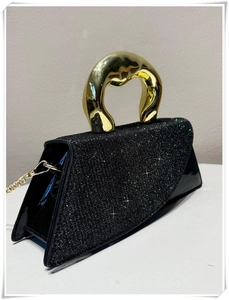 Detail of black sequined handbag with unique gold fluid-style metal handle and chain