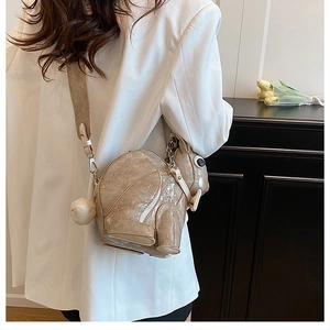 Chic model wearing a pearlescent gold rabbit crossbody bag with elegant white blazer