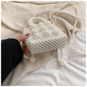 Detail of handmade pearl woven handbag featuring white ribbons and a pearl strap