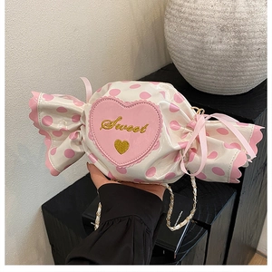 Detail of candy-shaped crossbody bag with pink heart embroidery and sweet gold lettering