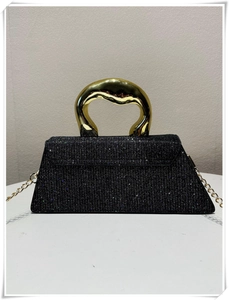 Detail of black sequin handbag featuring a streamlined gold metal handle and chain strap