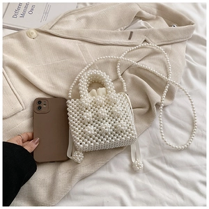 Détail du mini sac en perles blanches avec comparaison de taille par smartphone