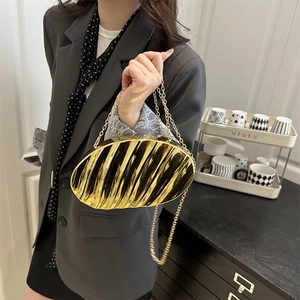 Golden shell pleated evening clutch bag with chain strap shown on a gray blazer