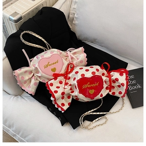 Detail of candy-shaped crossbody bags with Sweet embroidery and heart patterns on black blazer