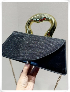 Detail of black sequin handbag featuring unique irregular gold metal top handle and chain strap