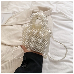 Macro view of woven faux pearl handbag with drawstring liner and elegant bead handle