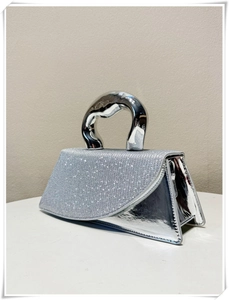 Detail of silver handbag featuring a rhinestone flap and unique irregular metal handle