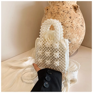 Detail of handmade pearl woven mini handbag with satin drawstring lining and ribbon bow