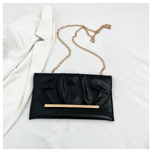 Détail du sac enveloppe noir brillant avec chaîne dorée et finitions plissées