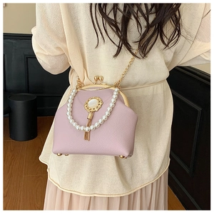 Detail of pink pearl handle bag with lychee pattern leather and gold fringe