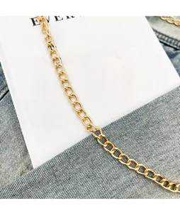 Détail macro de la bandoulière chaîne dorée brillante avec maillons ovales polis sur denim