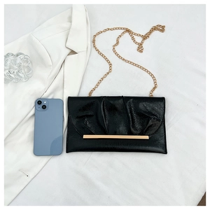 Détail du sac enveloppe plissé noir avec barre dorée et bandoulière chaîne élégante
