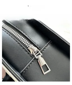 Close-up of smooth silver metal zipper and black pebble leather texture on a guitar bag