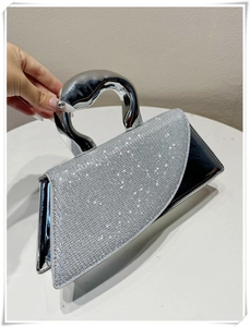 Close-up of geometric evening bag with silver crystals and artistic metal handle