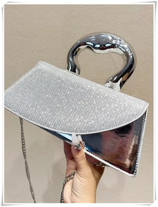 Detail of silver evening bag with rhinestone flap and sculptural wave handle