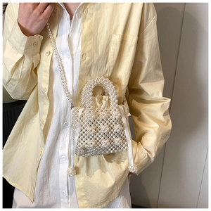 Detail of handmade pearl woven handbag with satin drawstring pouch and elegant chain