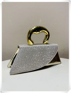 Close-up of asymmetrical silver sequin handbag with luxury metallic gold top handle