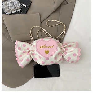 Detail of candy-shaped cream crossbody bag with pink polka dots and Sweet embroidery