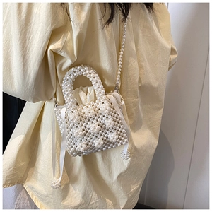 Detail of mini pearl woven bag with satin ribbon and drawstring inner lining on model