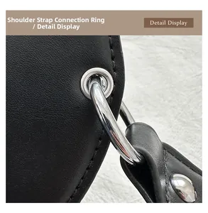 Close-up of silver metal strap rings and buckle on black guitar-shaped crossbody bag
