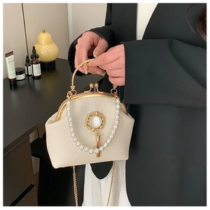 Detail view of a cream vintage clasp bag with pearl fringe and gold hardware texture