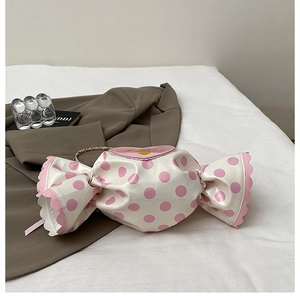 Detail of candy-shaped crossbody bag with polka dots, heart patch, and gold chain strap