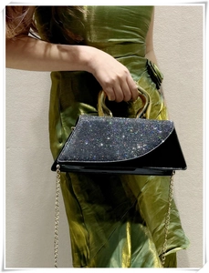 Close-up of black patent leather handbag with glitter crystals and golden metal handle