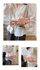 Detail of candy-shaped cream bag with pink polka dots, heart patch and gold chain strap