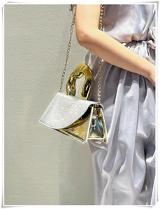 Detail of silver rhinestone evening bag featuring an artistic gold curved handle