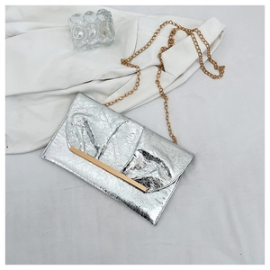 Détail du sac enveloppe argenté métallisé avec texture plissée et chaîne dorée
